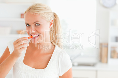 Blonde woman eating a slice of pepper