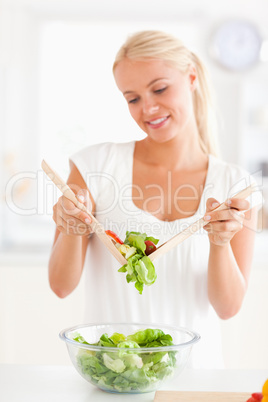 Portrait of a blonde woman mixing a salad