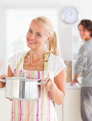 Portrait of a woman posing while her fiance is washing the dishe