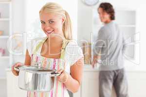 Portrait of a woman posing while a man is washing the dishes