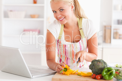 Close up of a blonde woman using a laptop to cook