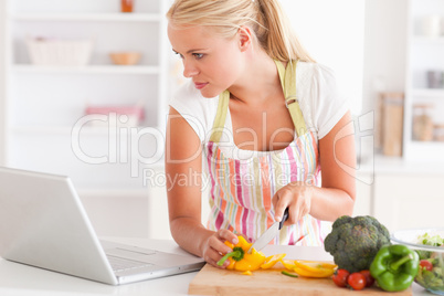 Close up of a woman using a laptop to cook