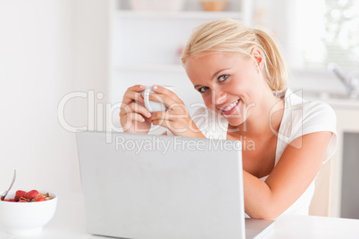 Woman having a cup of coffee while using her laptop Woman having a cup of coffee while using her laptop