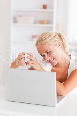 Portrait of a woman having a cup of tea while using her laptop