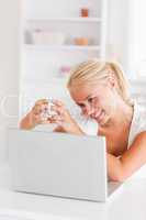 Portrait of a woman having a cup of tea while using her laptop