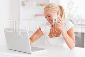Cute woman having a cup of tea while using her laptop