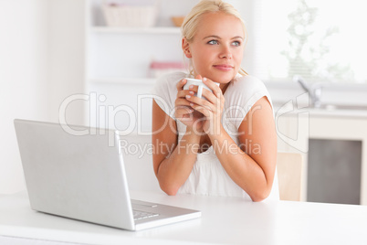 Cute woman having a cup of tea while with a notebook