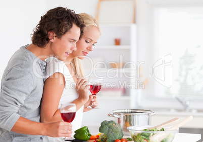 Couple cooking while having a glass of wine