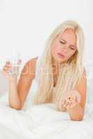 Portrait of a blonde woman looking at a pill