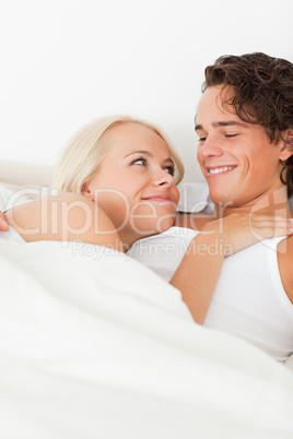 Portrait of a couple lying on a bed hugging