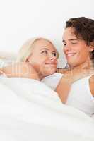 Portrait of a couple lying on a bed hugging