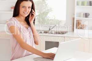 Woman telephoning while working at laptop