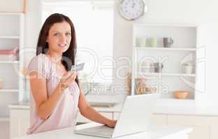 Woman showing credit card by laptop