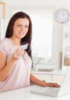 Woman showing credit card by notebook
