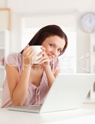 Woman holding cup of coffe at laptop