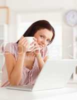 Woman holding cup of coffe at laptop