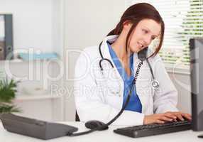 Female doctor telephoning and typing