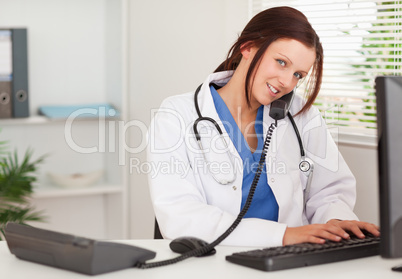 Female doctor is telephoning and typing