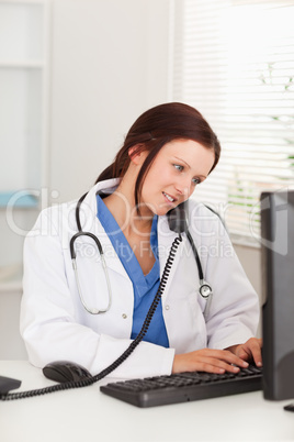 Female doctor typing and telephoning