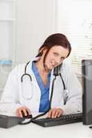 Doctor working with pc and telephoning