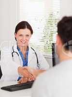 A female doctor is shaking hands with patient