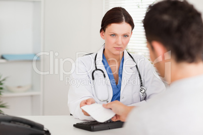 Serious doctor giving patient prescription