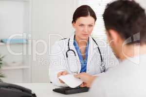 Serious doctor giving patient prescription