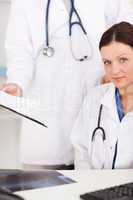 Doctor showing female doctor a file in office