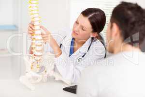 Female doctor pointing on bone in spine