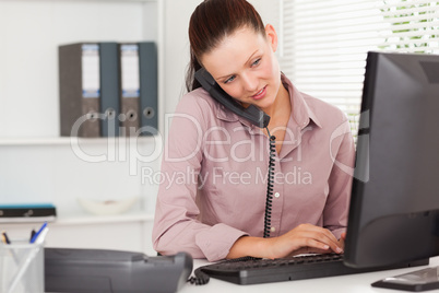 Businesswoman telephoning and typing