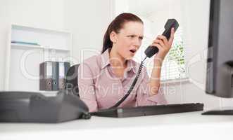 Depressed businesswoman shouting at telephone