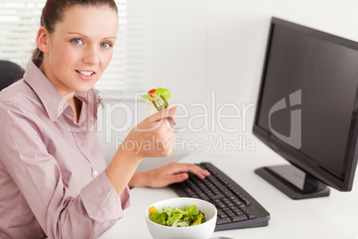 Businesswoman in office eating salad