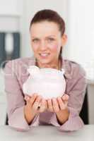 Businesswoman holding piggy bank in office