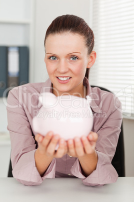 Businesswoman holding a piggy bank in office