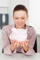 Businesswoman holding piggy bank at workplace