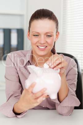 Businesswoman putting money in piggy bank