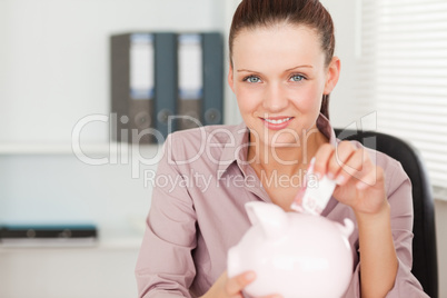 A female inserting money in piggy bank