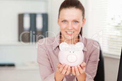 Businesswoman holding a piggy bank in office