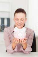Businesswoman looking at piggy bank