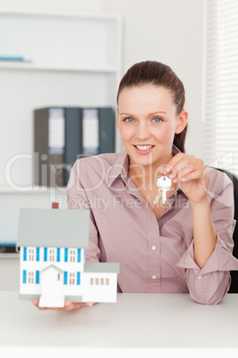 Businesswoman showing keys and model house