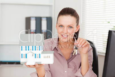 Businesswoman shows keys and model house