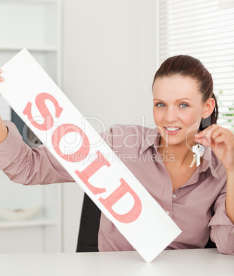 Businesswoman holding keys and sold sign