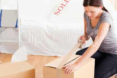 A woman closing a cardboard with tape