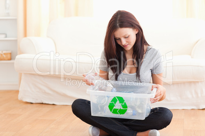 Cute woman putting bottles in a recycling box