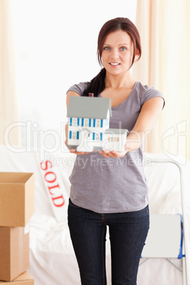 Portrait of a young woman holding a model house