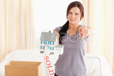 Young woman holding model house and keys