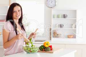 Red-haired woman mixing a salad looking into the camera