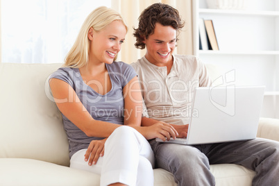 Smiling in love couple using a laptop