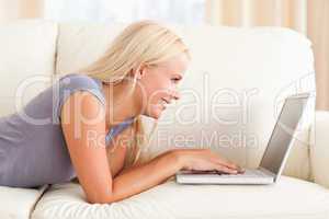 Woman lying on a sofa while using a laptop