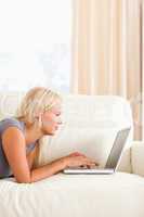Woman lying on a couch while using a laptop
